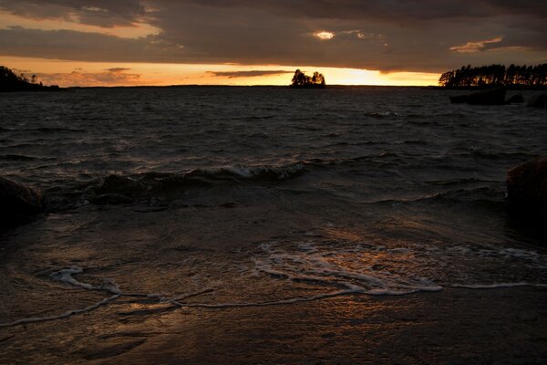 Small waves and foam near the beach at sunset