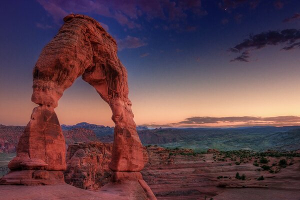 Stone arch in the canyon under the blue sunset