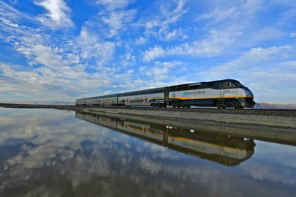 Between two worlds without borders (mirror image of a train under a blue sky)