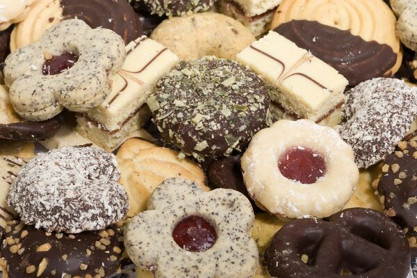 Galletas surtidas, en chocolate blanco y negro, espolvoreadas con nueces con mermelada agregada. En forma de flores y pretzels