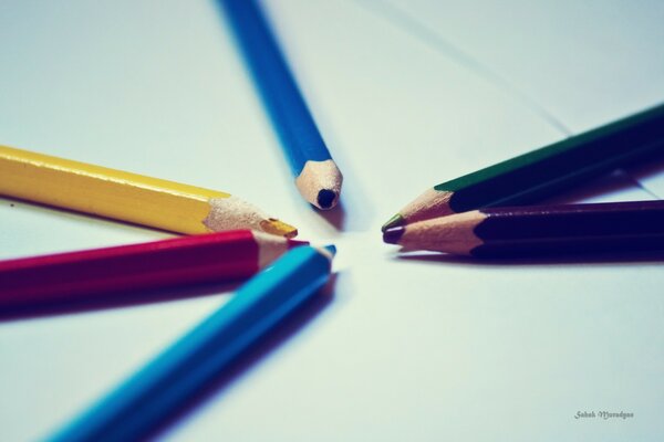 Six crayons sur une feuille blanche