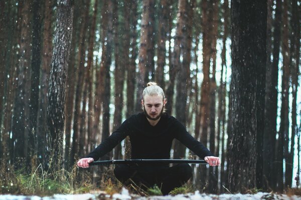 Homme avec une épée sur fond de troncs d arbres