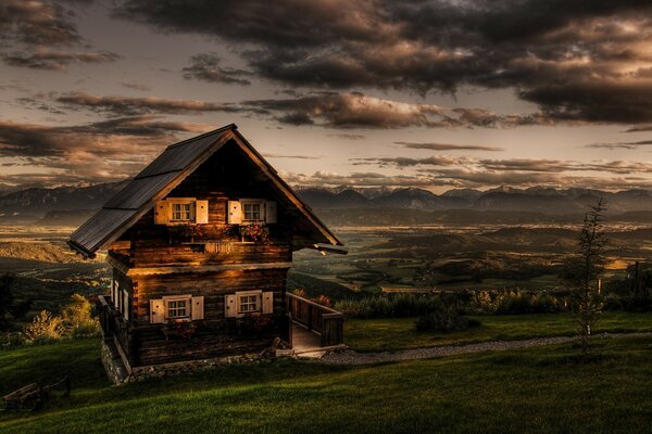 Casa de madeira em um campo no fundo de um céu nublado e noturno