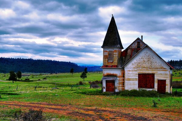 An old abandoned house with a turret in the middle of a deserted plain