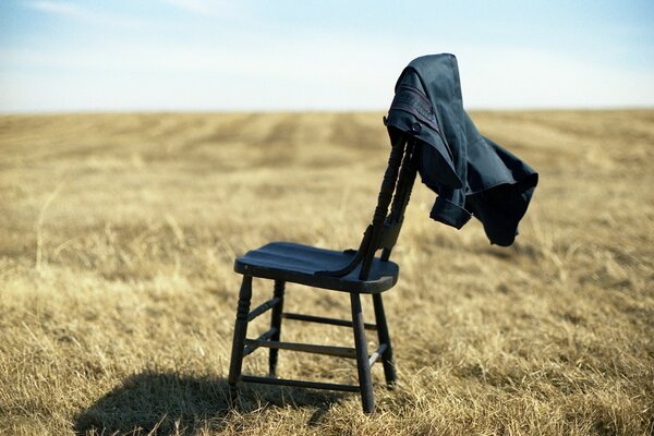 A chair with a jacket standing in a field