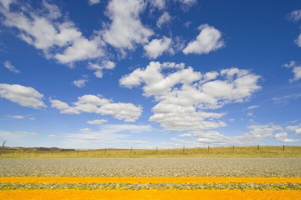 Champ, route et nuages blancs