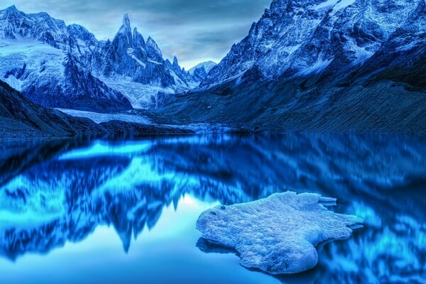 A mountain range with a lake in blue tones