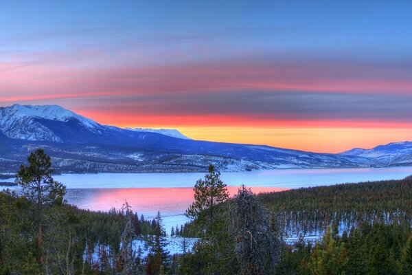 Forest and lake on the background of mountains and evening sky