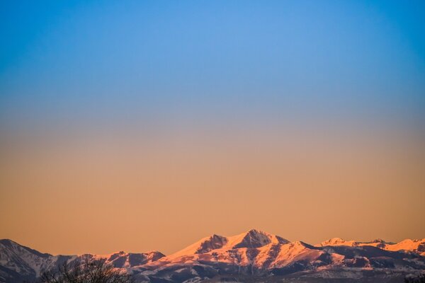 Amanecer naranja más allá de las altas montañas