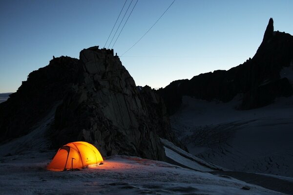 Tent with a lantern at dusk in the mountains