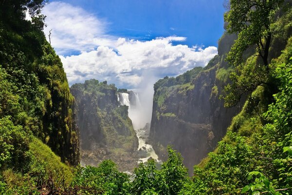 Vida selvagem. Montanhas verdes e uma cachoeira no fundo do céu azul