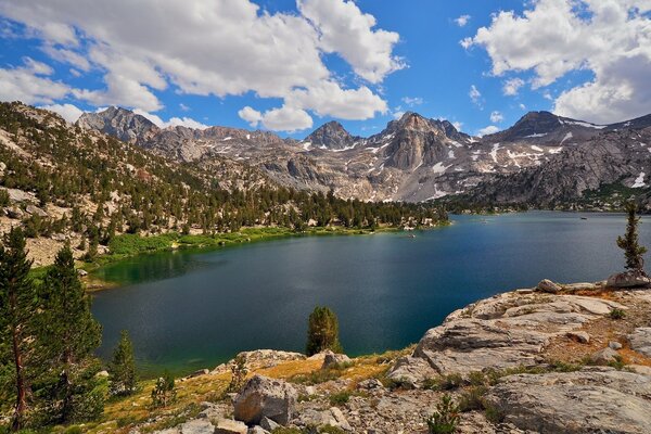 Paysage. Lac dans les montagnes, les nuages dans le ciel et les sommets enneigés