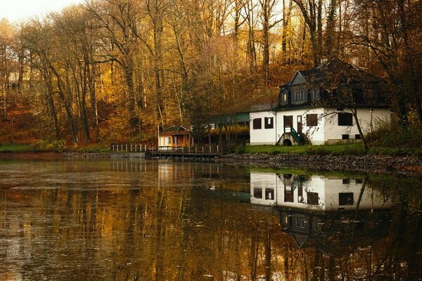 Biały domek nad jeziorem jesienią