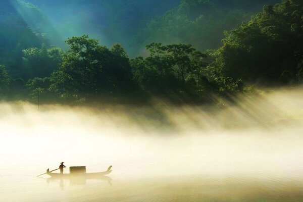 A large boat is floating on a foggy river