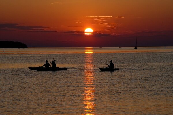 People in boats on the background of the setting sun