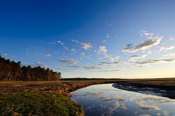 O rio que passa entre os campos e o céu refletido