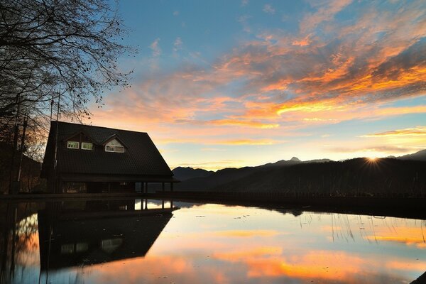 Haus bei Sonnenuntergang am Wasser