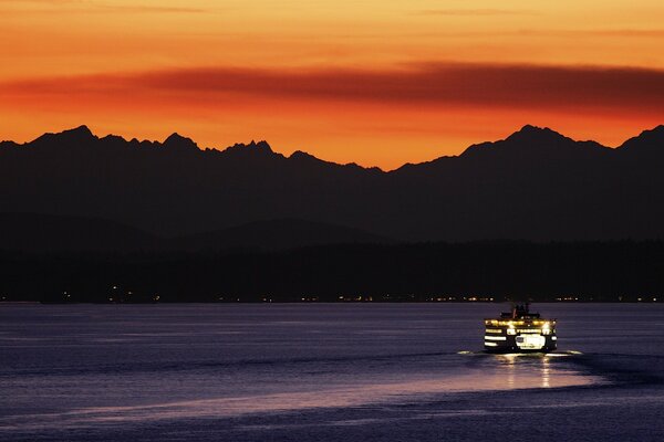 A motor ship in a night river against the background of dark mountains