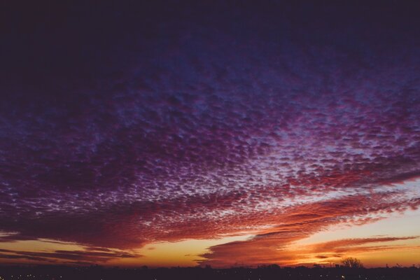 Nubes púrpuras desmenuzables en todo el cielo cambiando a rojo-naranja