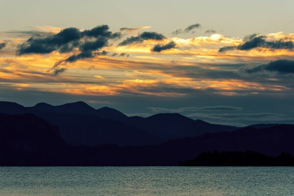 Sonnenuntergang über dem Wasser vor dem Hintergrund der Berge