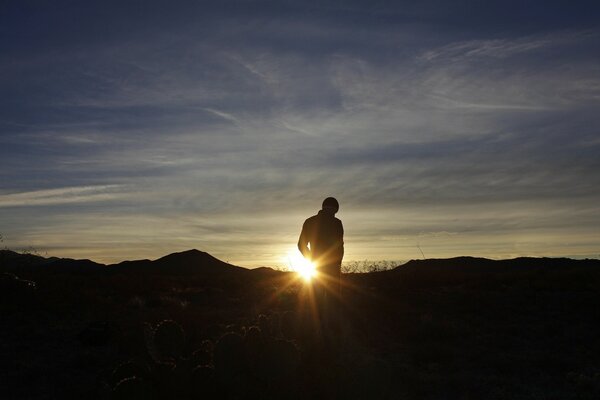 A man stands against the background of the sunset