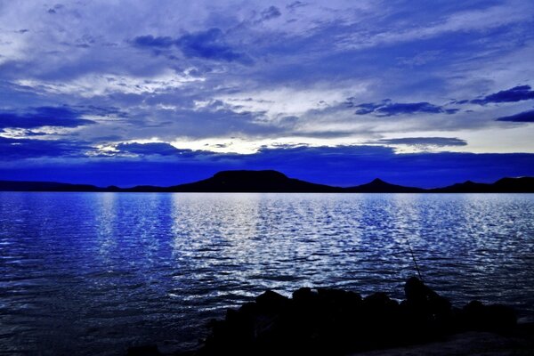 Silhouettes of mountains clouds and water