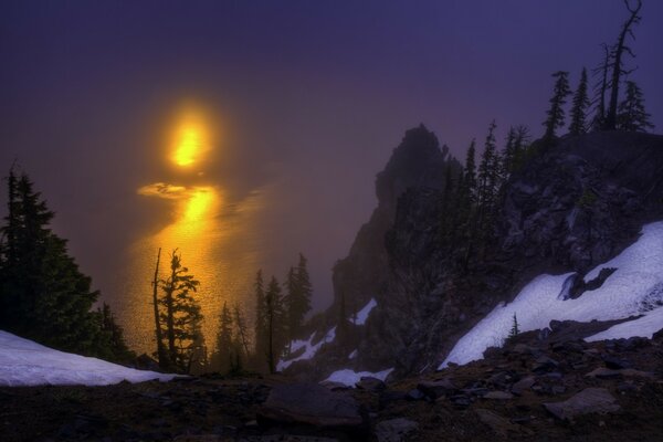 山和圣诞树在一个下雪的夜晚对发光的月亮的背景