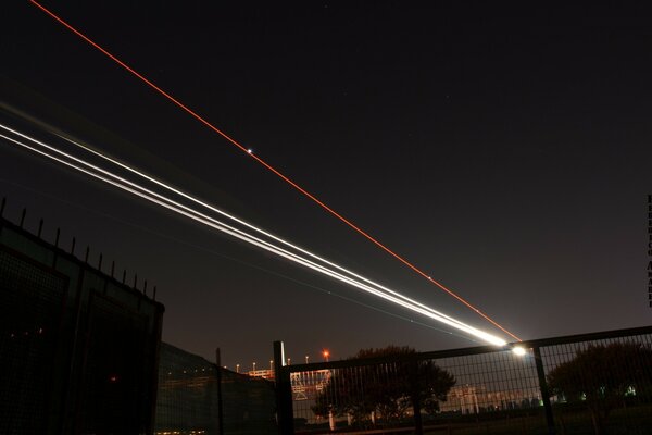 Dans le ciel nocturne, des lignes droites vives sont visibles