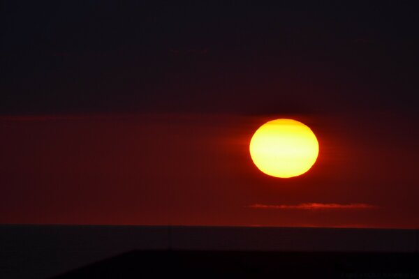 El sol Poniente contra el cielo carmesí