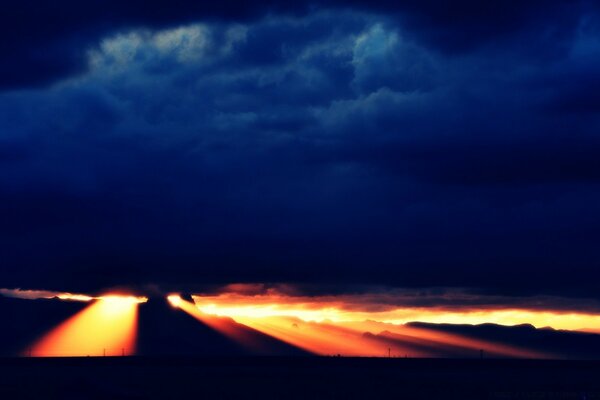 Cielo al atardecer con nubes a través de las cuales los rayos del sol penetran