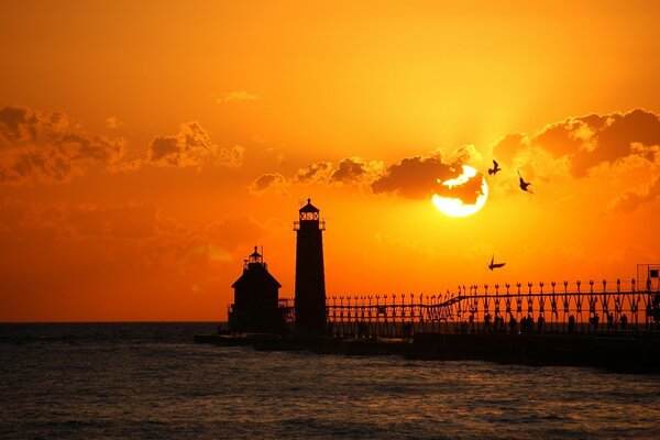 Hermosa puesta de sol de la tarde junto al agua y los faros