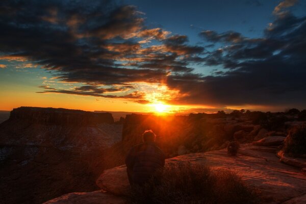 Homme assis admirant le coucher du soleil