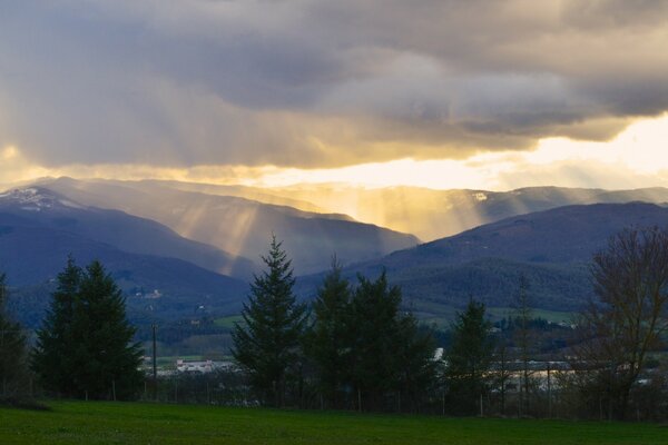 The sun s rays break through the clouds over the mountains