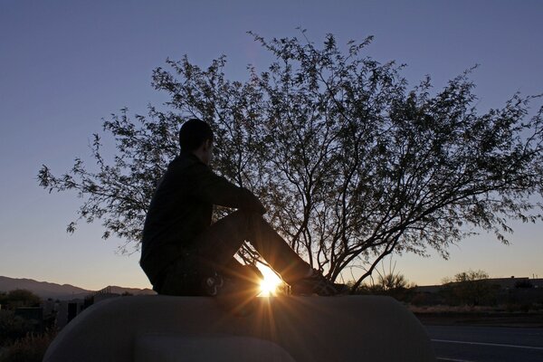 Homem admira o céu ao pôr do sol