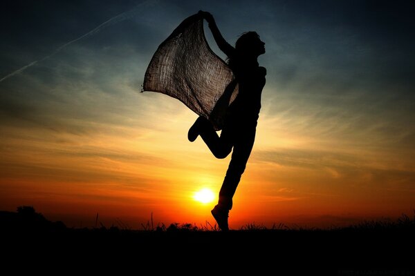 Silhouette of a soaring girl at sunset