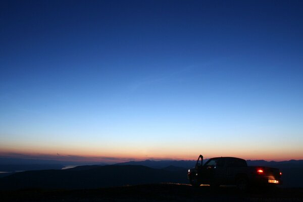 Coche en el fondo de la puesta de sol que se va