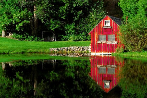 Maison rouge avec balançoire au bord du lac