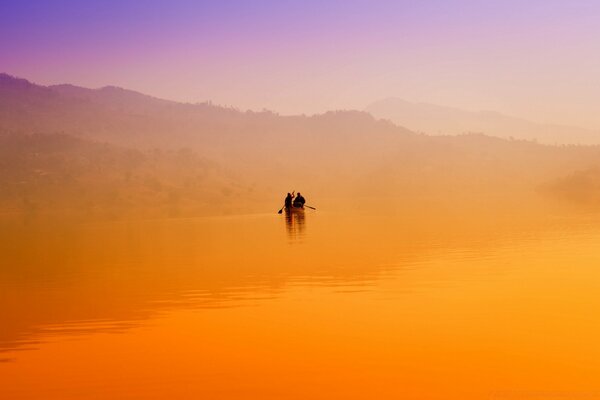 Bateau avec des gens au coucher du soleil orange