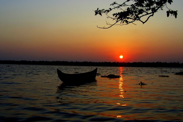 A boat in the water against the background of a red sunset