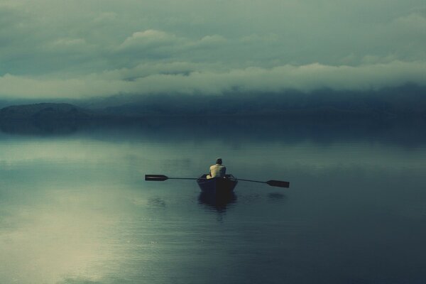 A fisherman on a boat sails off into the sunset