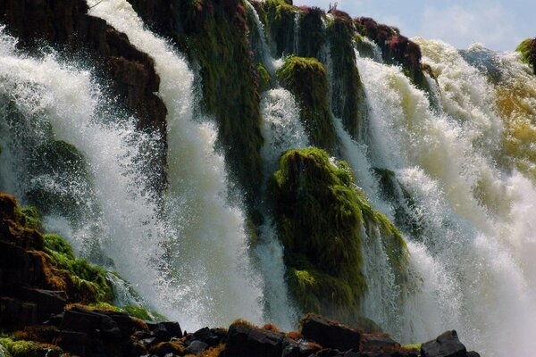 Stürmischer Wasserfall unter hohen Berghängen