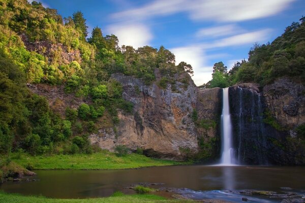 Sommerlandschaft eines Wasserfalls unter Bäumen am Berghang