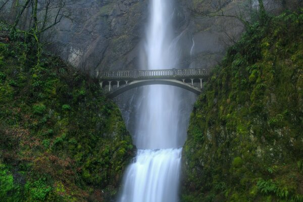 Ein großer und mächtiger Wasserfall geht über eine Brücke in den Fluss hinunter