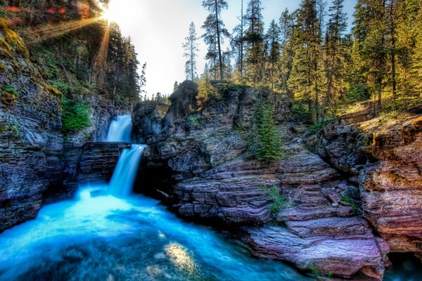 Berg Wasserfall auf dem Hintergrund von Wald und Sonne