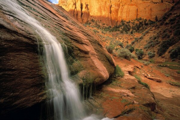 Wasserfall auf dem Hintergrund von Steinen und Fluss