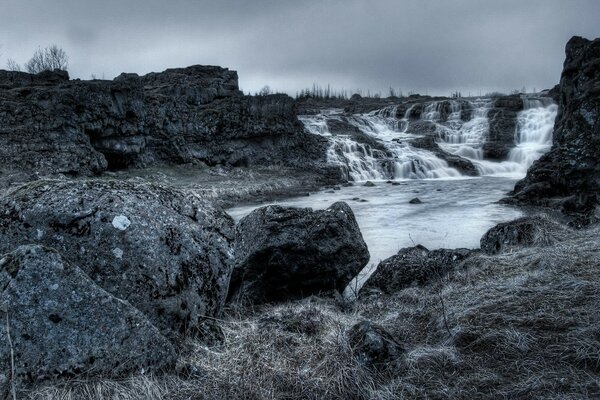 Black and white landscape of a small waterfall on a rocky riverbank