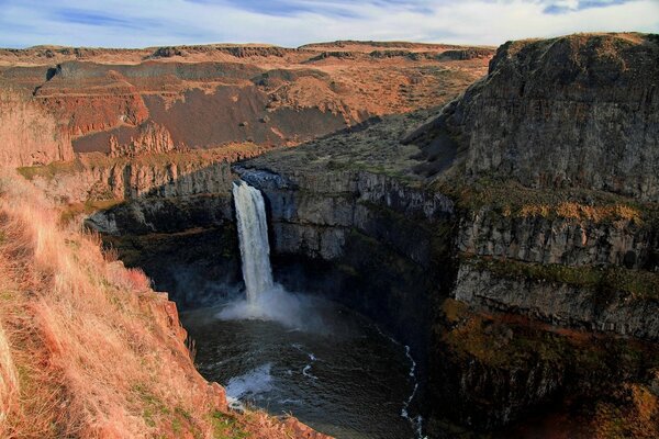 Una poderosa cascada en el cañón desemboca en un río turbulento