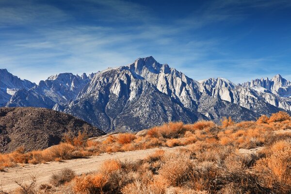 Sandy road on the background of mountain ranges