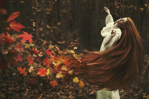 A girl with red hair, a train of hair from autumn bright leaves