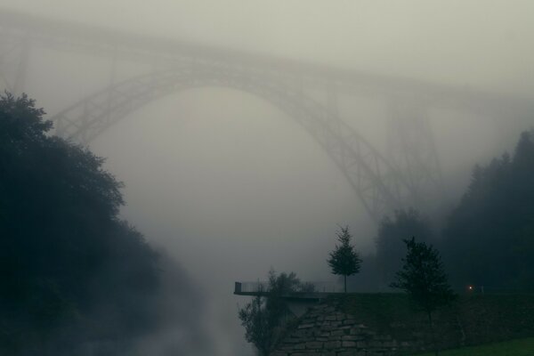 Puente en la niebla al amanecer. Paisaje